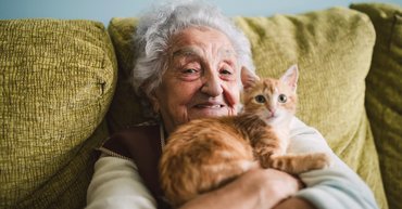 Idős néni egy vörös macskát tart a kezében