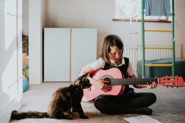 egy gitározó gyerek macskával