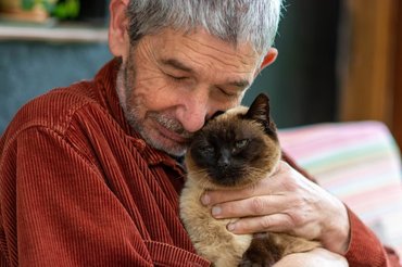eldelry man hugging a cat